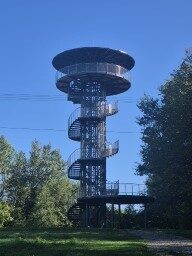 Stalowa wieża widokowa ze spiralnymi schodami i zadaszonym tarasem.
